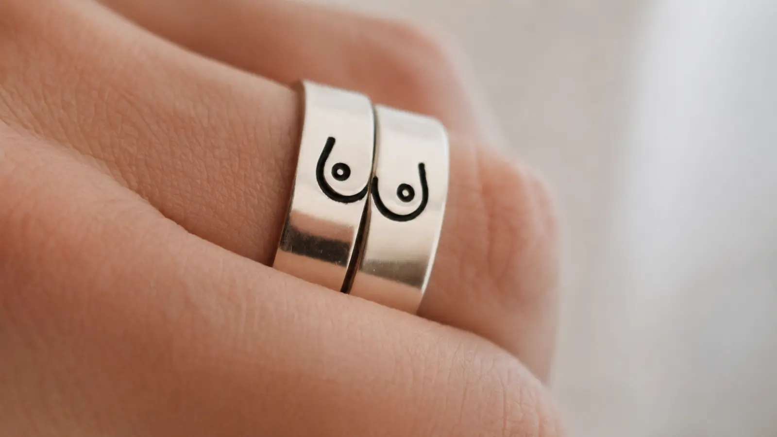 Two wedding rings featuring a funny custom engraving design displayed together on a person's finger