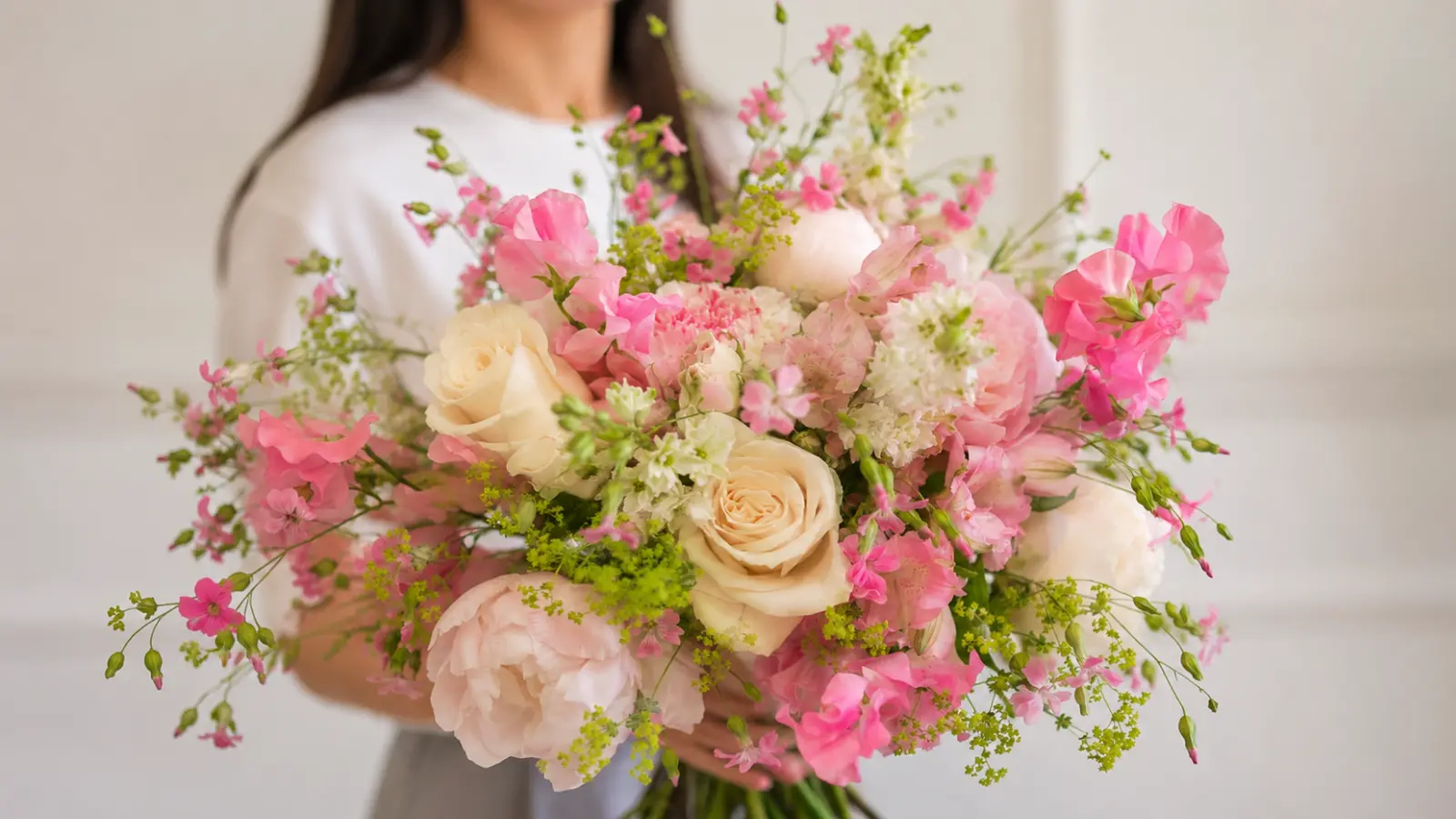 Large garden-style pink wedding bouquet featuring roses, peonies, sweet peas and fresh greenery