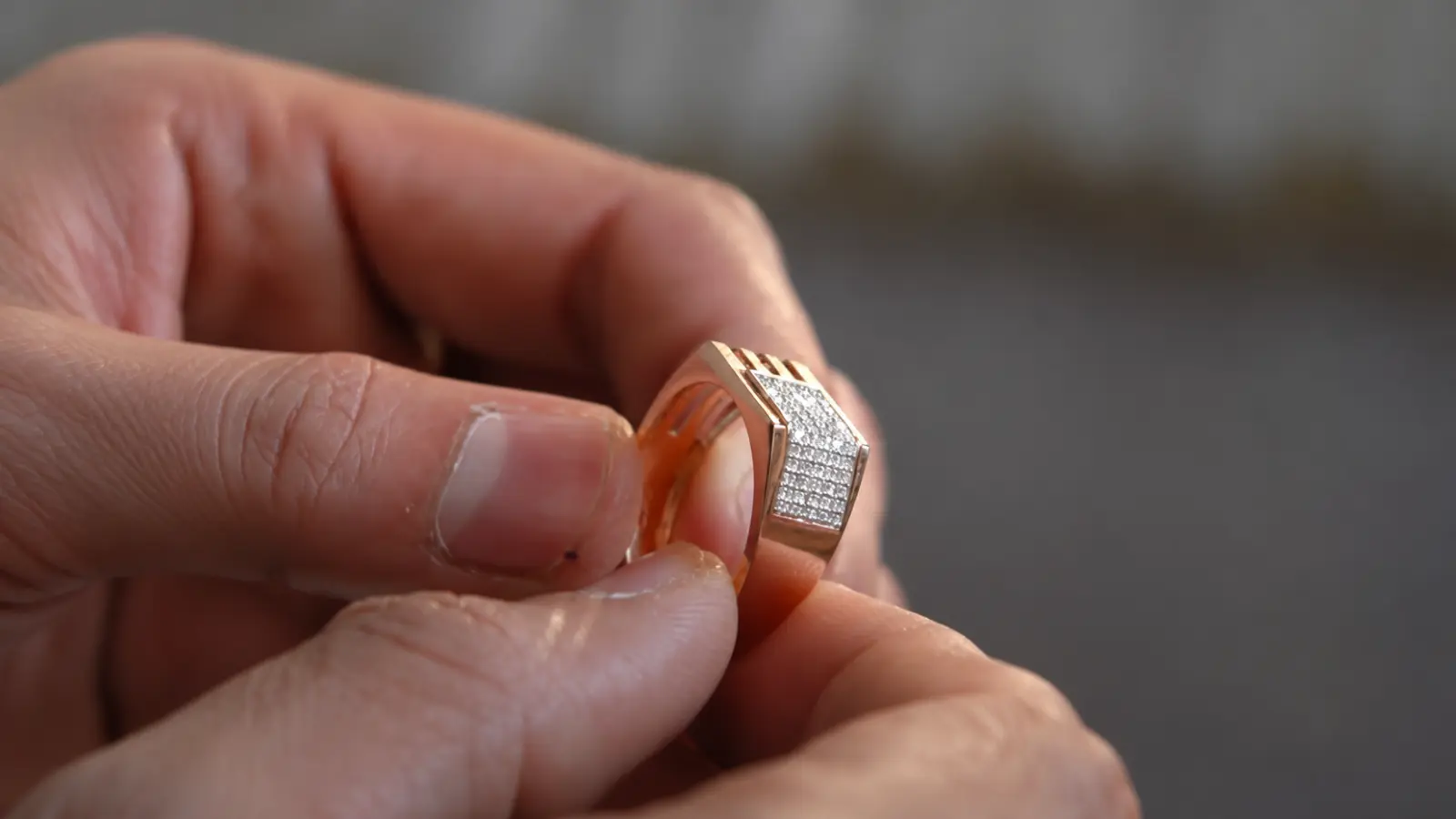 A close-up of a geometric men's wedding ring with pavé diamonds and a bold angular yellow gold design