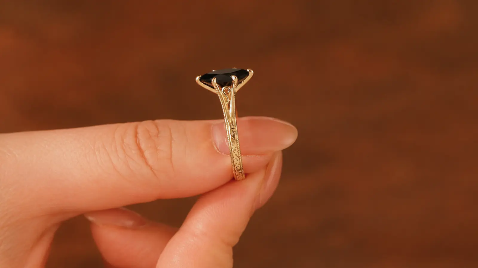 A side profile of a gothic black solitaire ring displaying intricate gallery details beneath a black gemstone setting