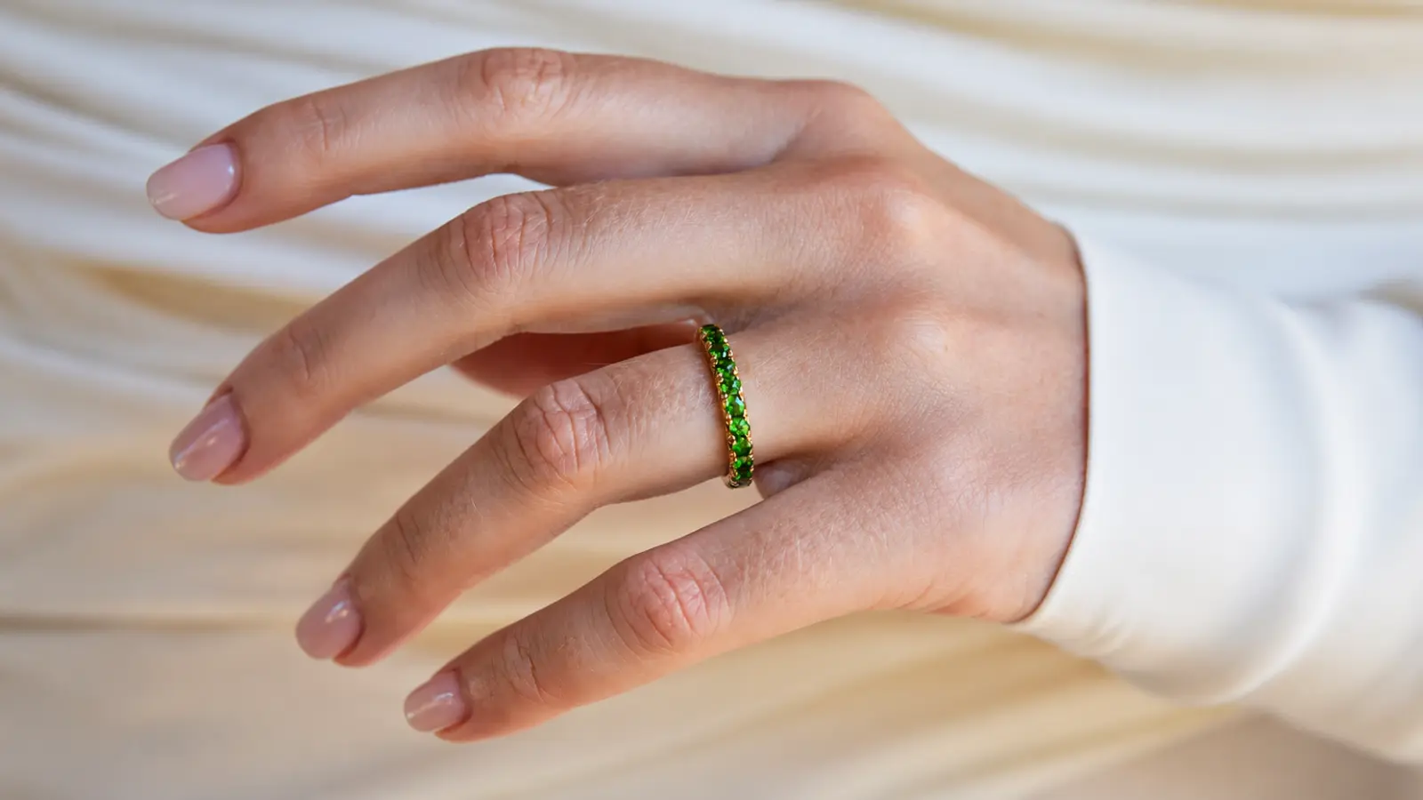Green gemstone eternity wedding band worn as part of a bridal stack