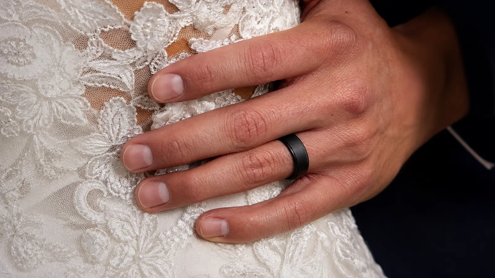 Groom wearing a black silicone wedding band while holding his bride in a lace wedding dress Men's Silicone Wedding Bands