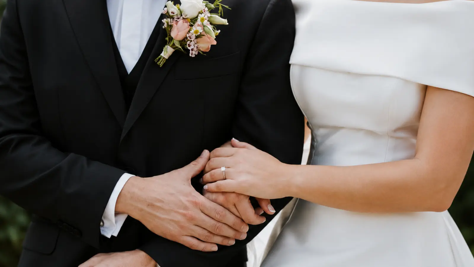Bride without a wedding bouquet standing beside the groom wearing a floral boutonniere
