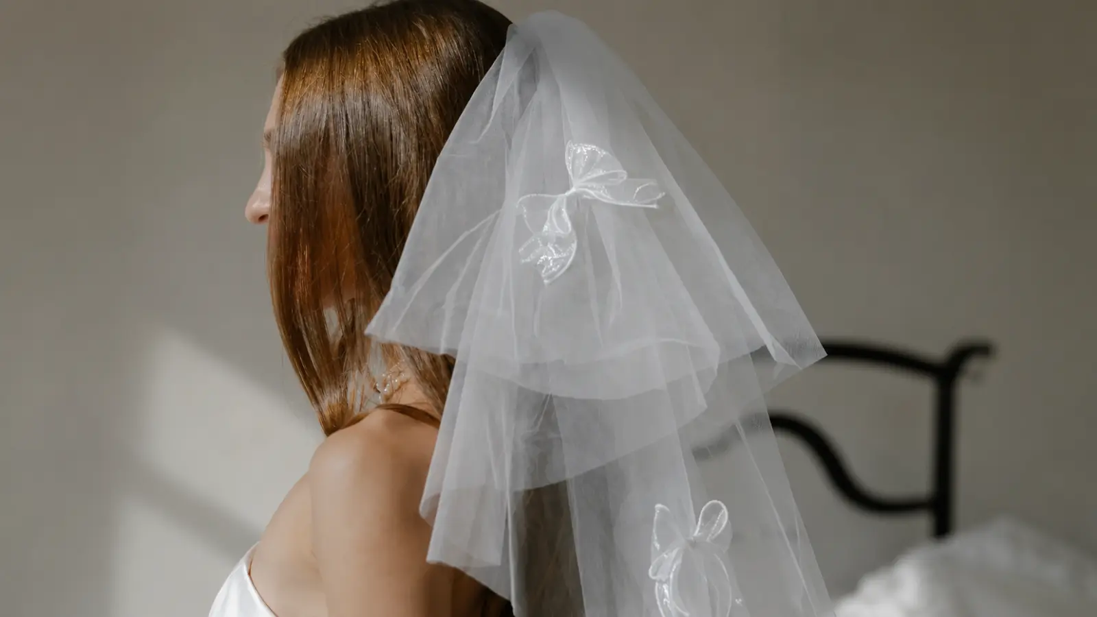 Bride wearing a half-up wedding hairstyle with a lightweight veil and delicate bow appliqués