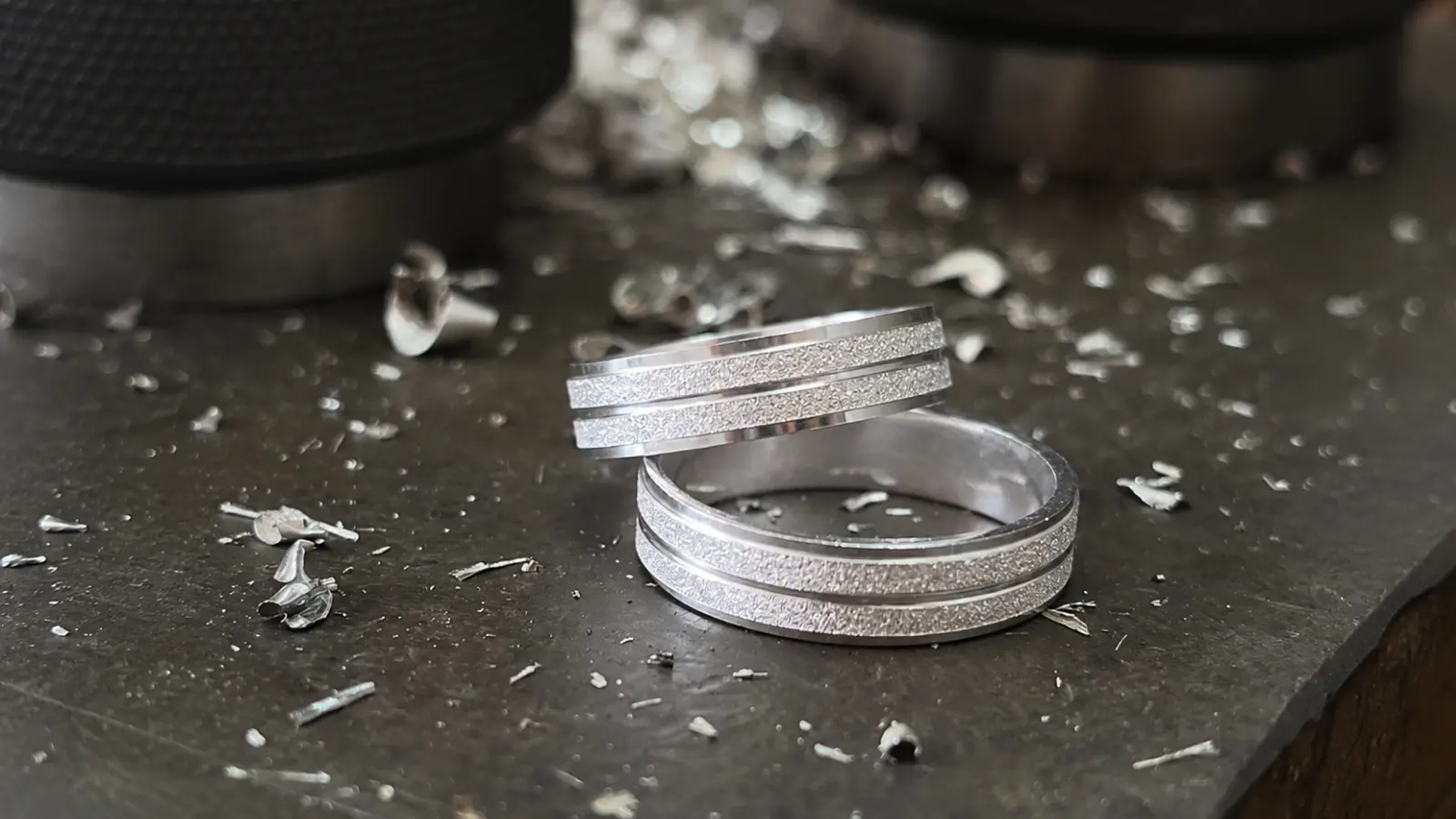 Two handcrafted platinum wedding rings are displayed on a jeweler's workbench, highlighting fine craftsmanship, textured finishes and the exceptional durability of platinum jewelry
