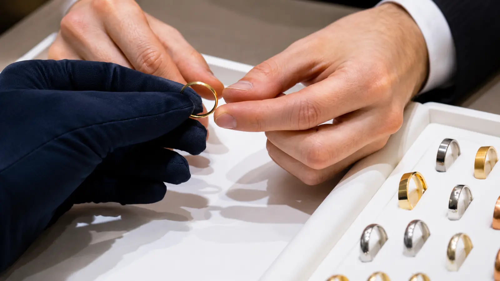 A jeweler assisting a customer in selecting the correct wedding ring size by trying different band sizes