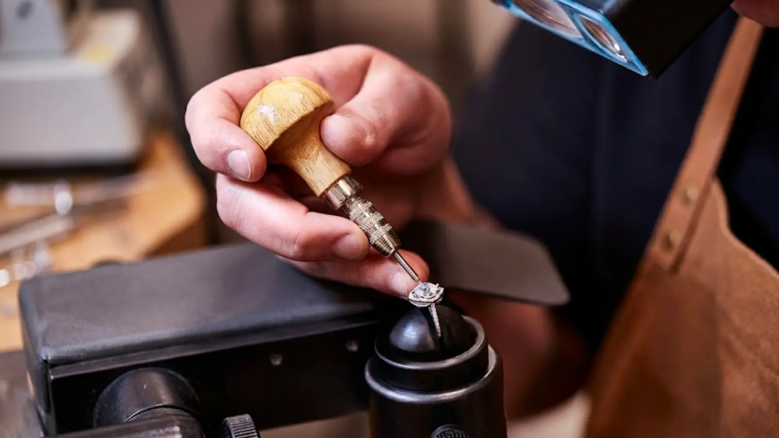 A skilled jeweler using precision tools and magnification to adjust a diamond engagement ring, demonstrating the detailed craftsmanship involved in a professional wedding ring upgrade and jewelry restoration process
