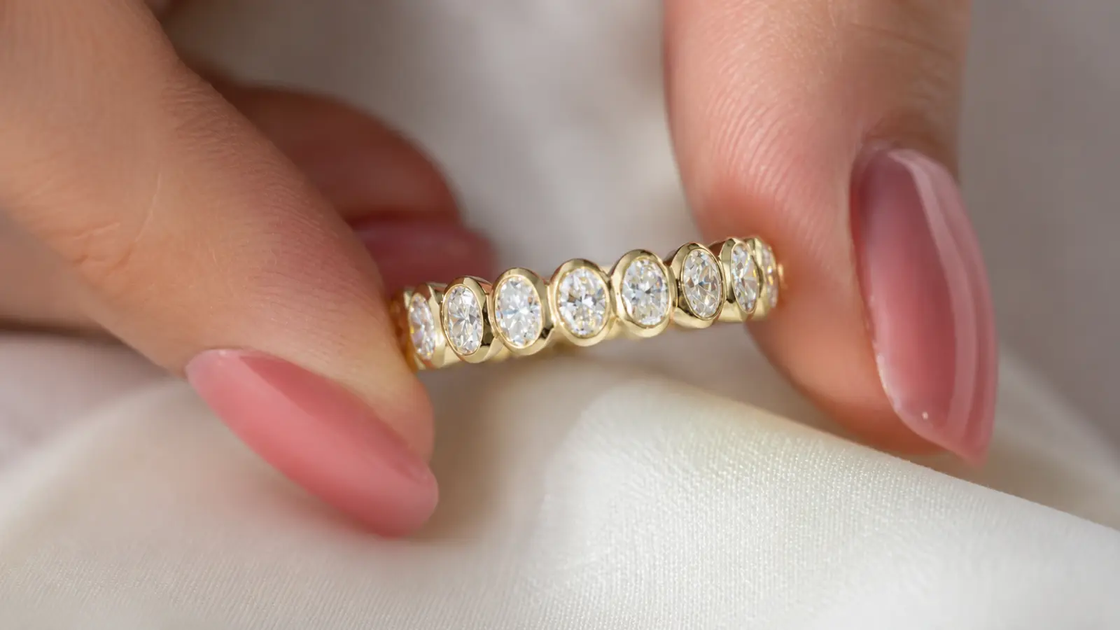 A close-up of a lab-grown diamond eternity band highlights evenly matched round diamonds set in polished yellow gold
