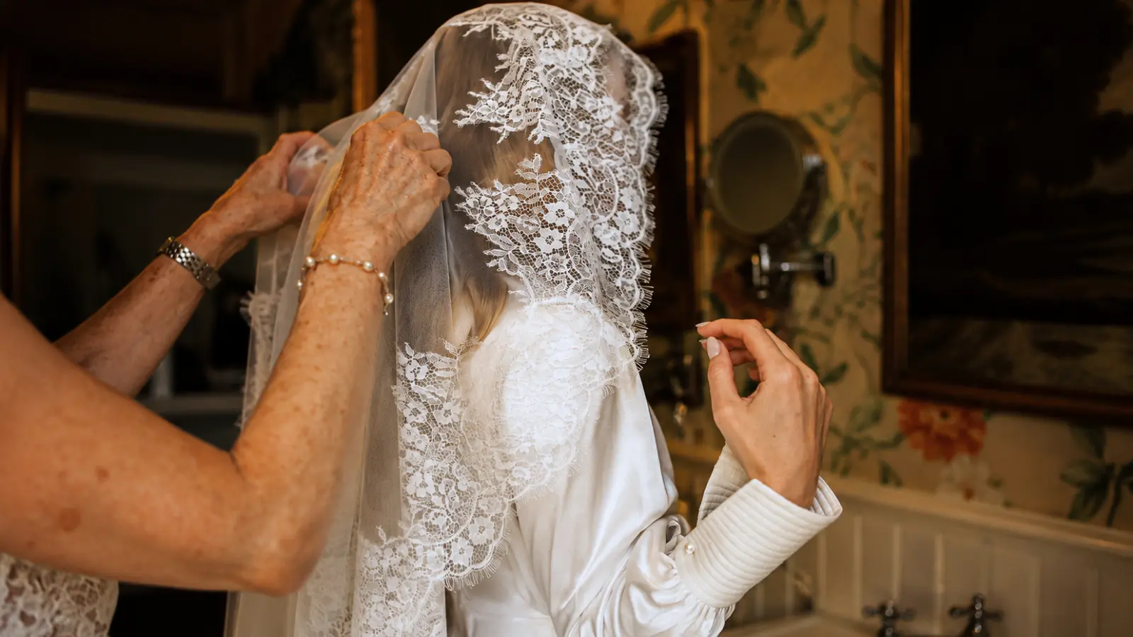 Bride having a lace wedding veil carefully secured over an elegant bridal hairstyle before the ceremony