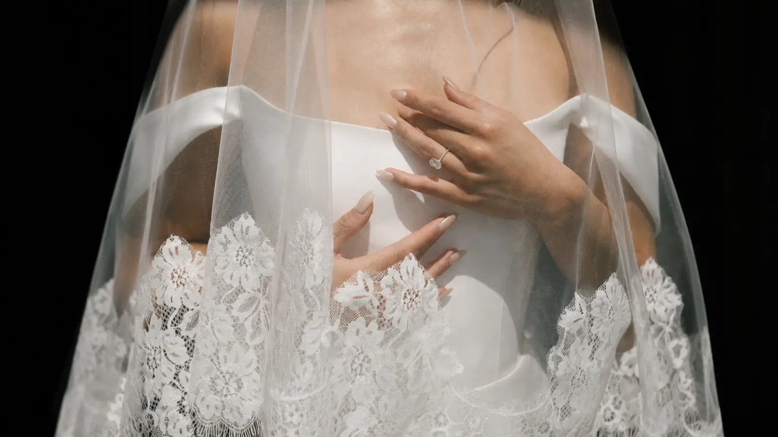 Close-up of a lace wedding veil with floral embroidered trim over a satin bridal gown Lace Wedding Veil