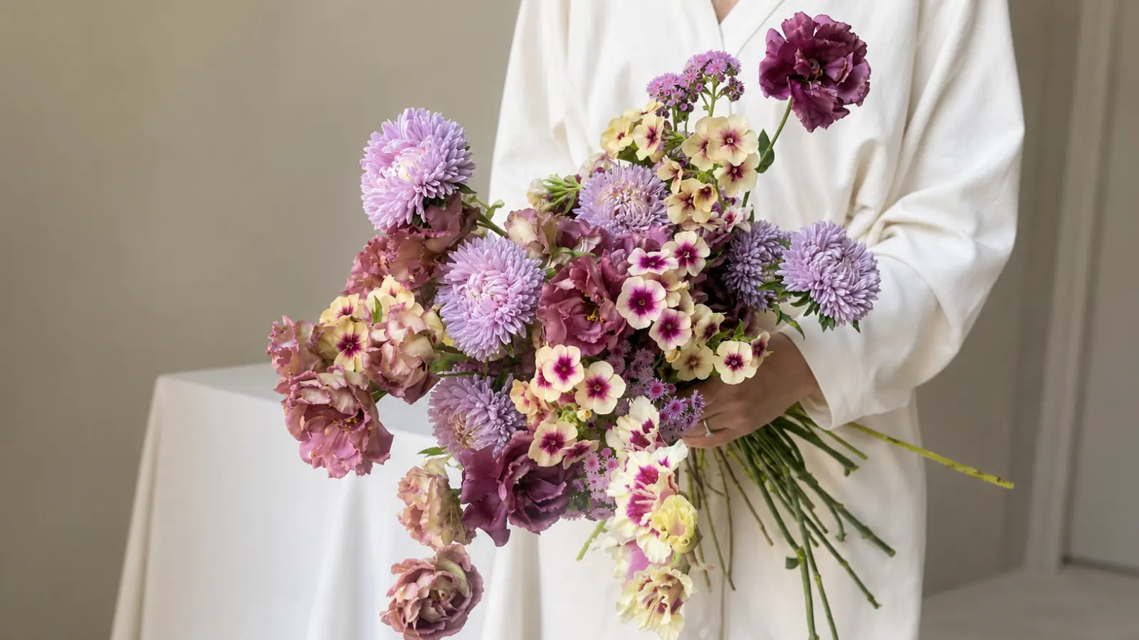 Bride holding a lilac wedding bouquet with chrysanthemums, lisianthus and delicate garden flowers