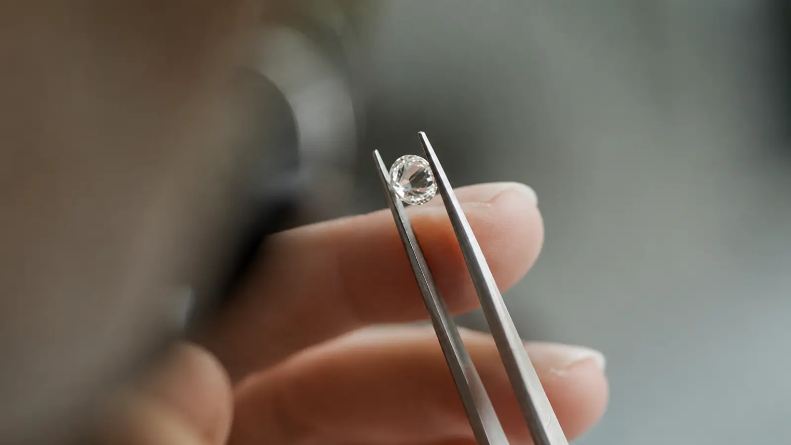 Jeweler examining a loose round diamond with precision tweezers before setting it into a men's diamond wedding band
