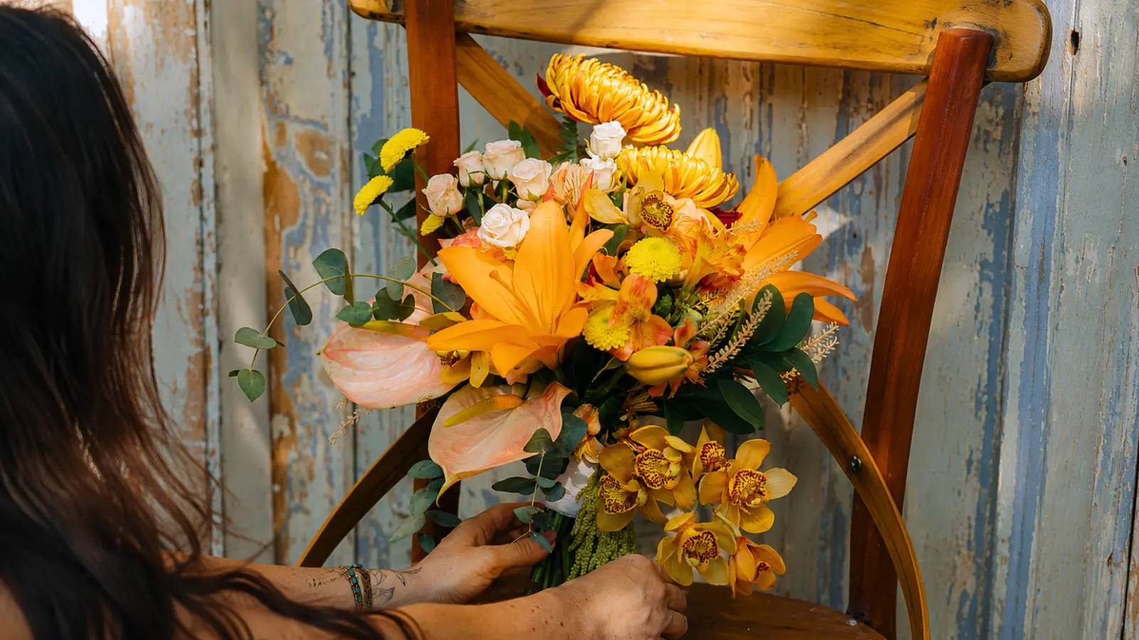 Florist arranging a luxury orange wedding bouquet with orchids and lilies