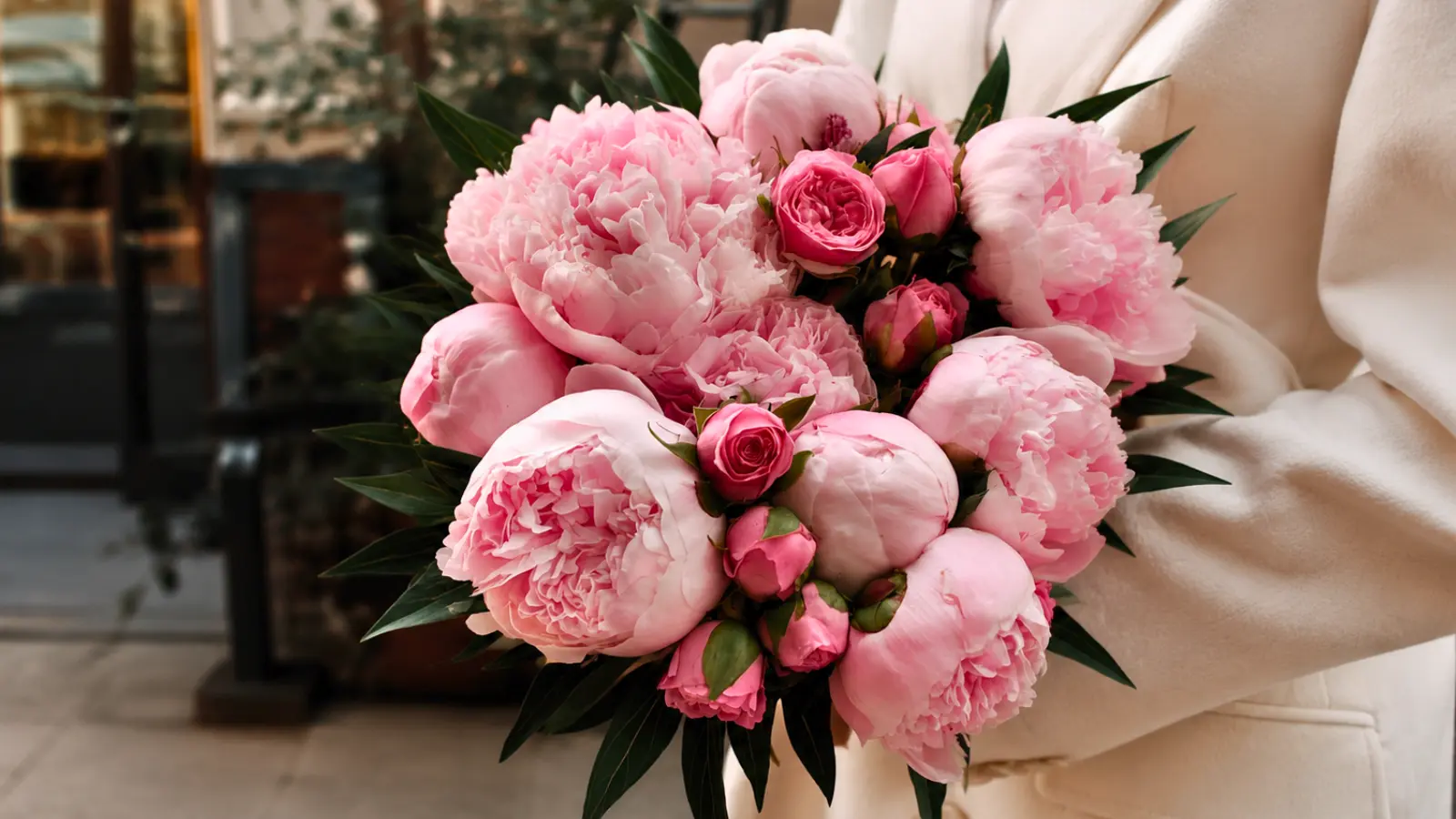 Bride holding a full wedding bouquet with blush peony wedding bouquets, pink garden roses, and rich green foliage
