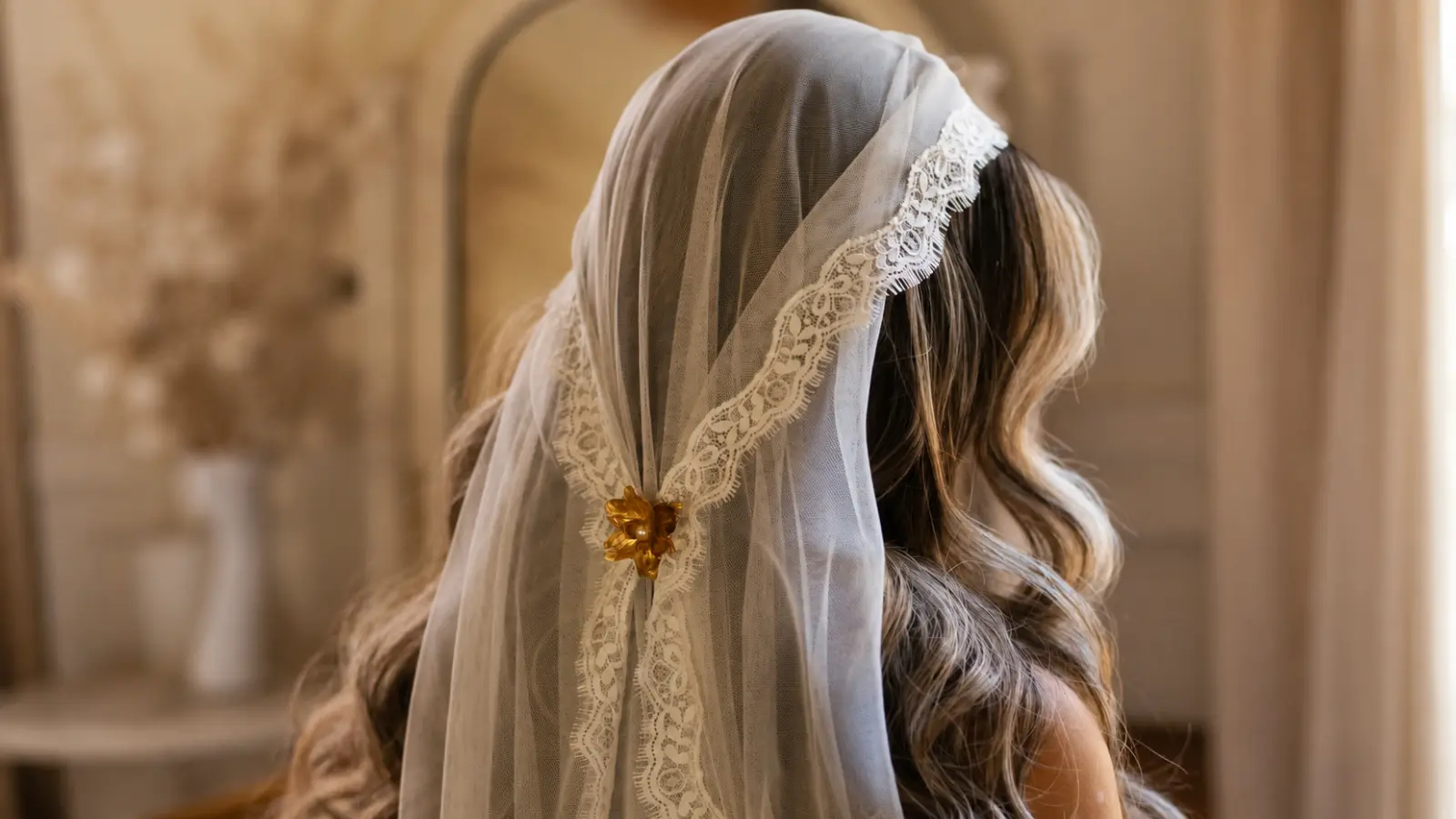 Bride wearing a lace mantilla wedding veil secured with a decorative brooch, representing traditional bridal symbolism and heritage Wedding Veil Meaning