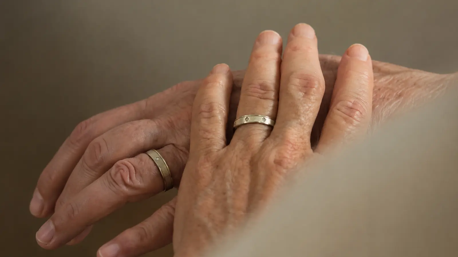 Two hands wearing matching classic wedding bands with subtle detailing in a timeless and elegant close-up portrait