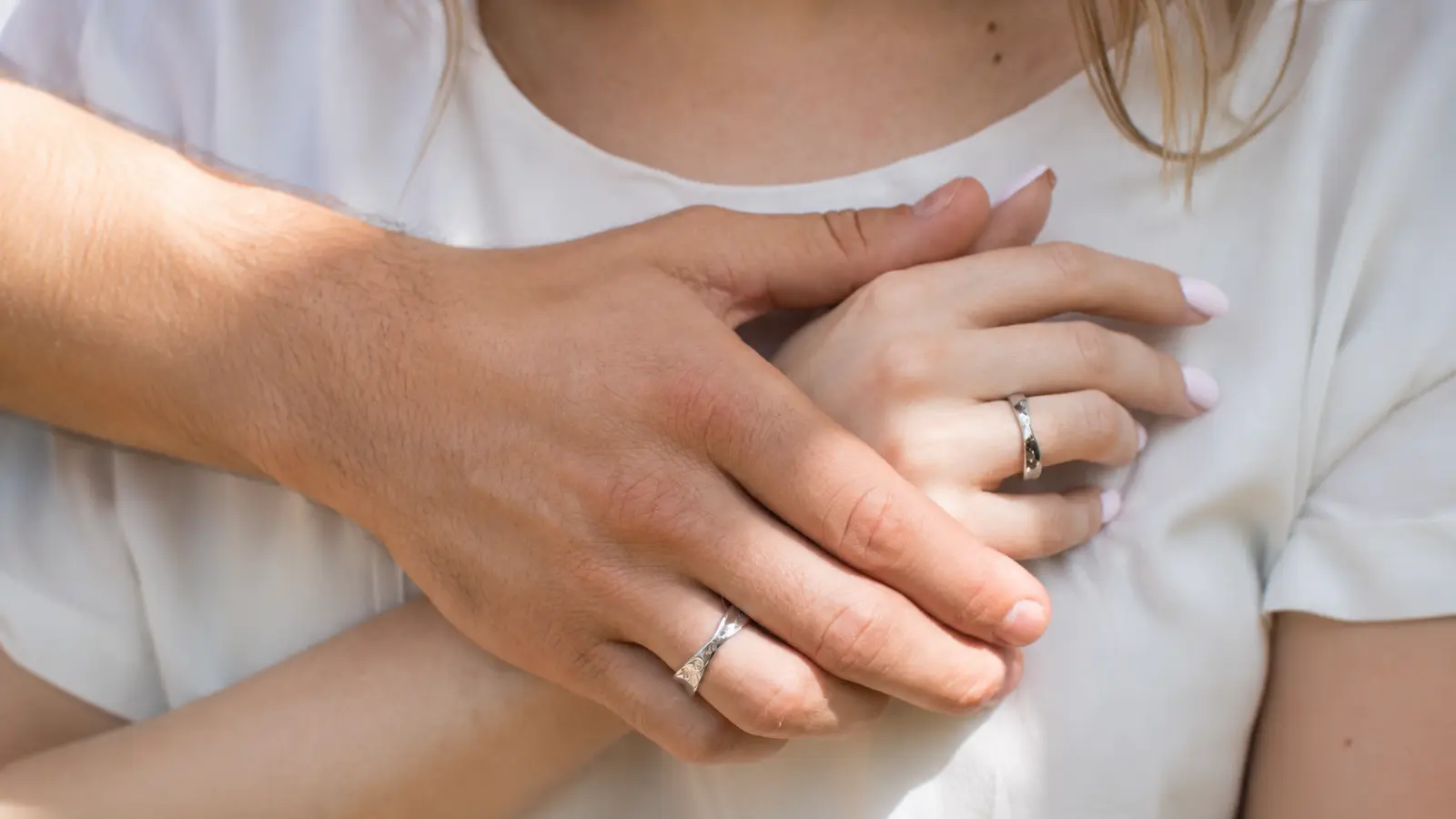 A couple gently holds hands while wearing matching white gold wedding bands, illustrating a minimalist coordinated ring style that balances elegance with everyday comfort Matching Wedding Bands