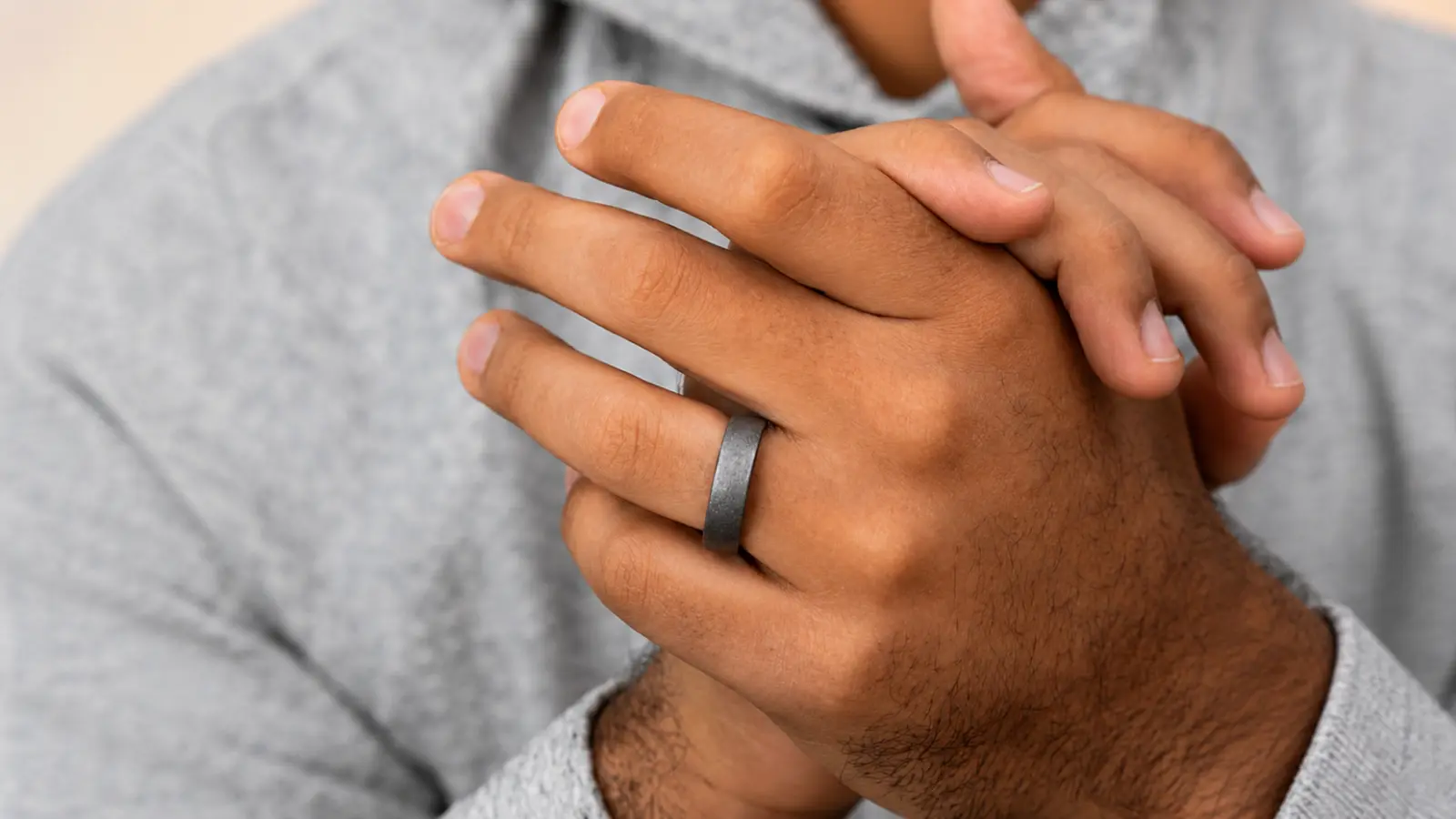 A close-up of a hand wearing a matte meteorite wedding ring emphasizes its subtle finish, authentic meteorite texture and clean modern profile
