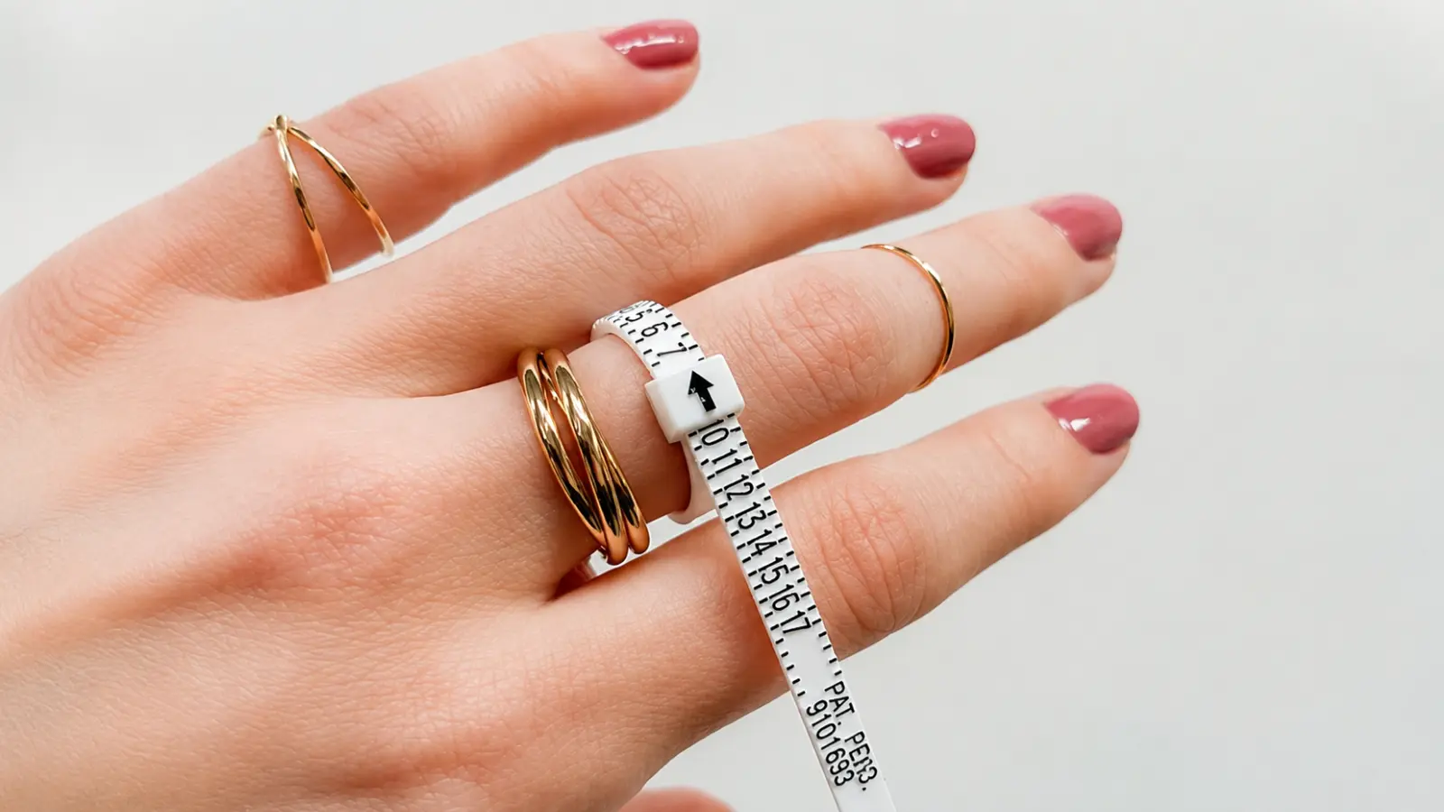 A flexible ring sizer wrapped around a finger to measure the correct wedding ring size before purchasing a ring Wedding Ring Size Guide