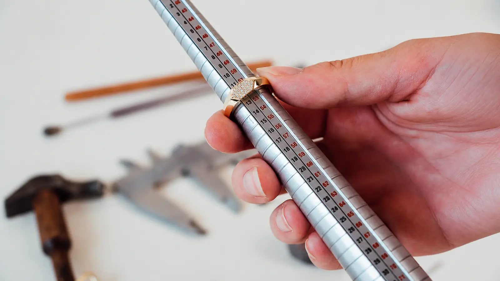 A jeweler measures a ring on a sizing mandrel, demonstrating the importance of accurate sizing before purchasing a tungsten wedding ring