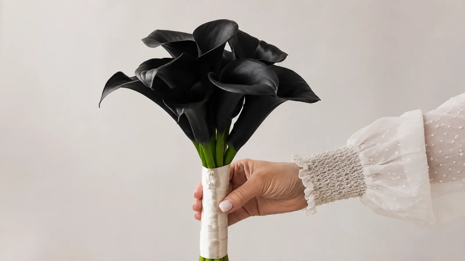 Hand holding a minimalist black calla lily wedding bouquet