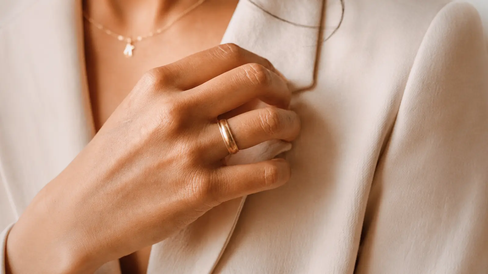 A hand wearing minimalist modern stacking wedding rings with slim gold bands and refined contemporary detailing