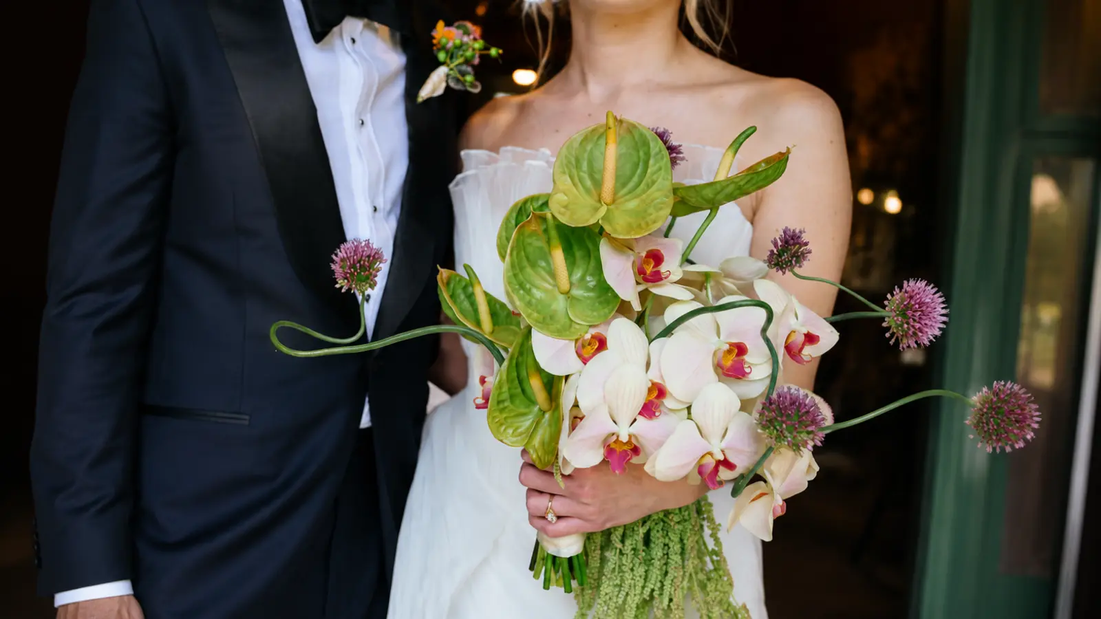 Bride holding a modern wedding bouquet with orchids and green anthuriums