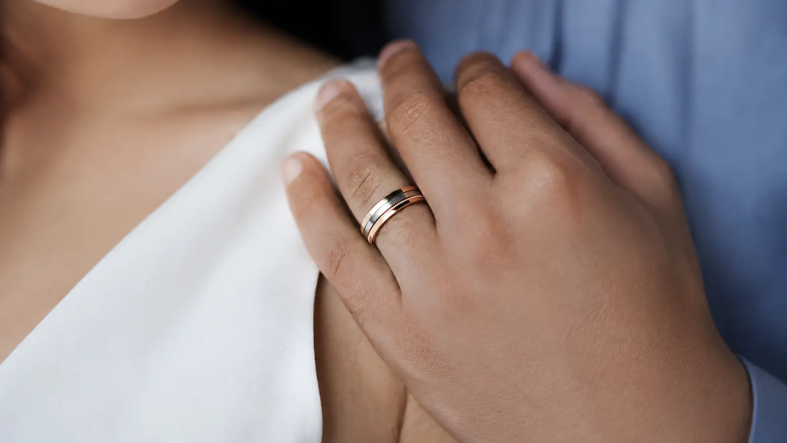 A hand wearing a modern two-tone wedding band featuring clean geometric styling with contrasting precious metal finishes