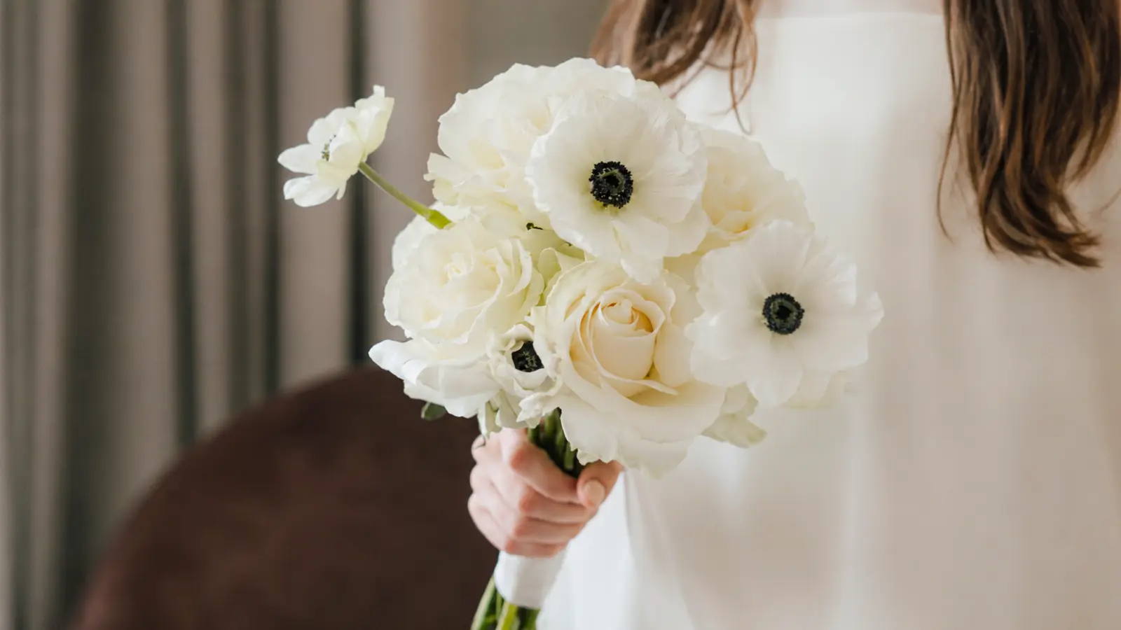 Bride holding a modern white wedding bouquet with anemones and roses