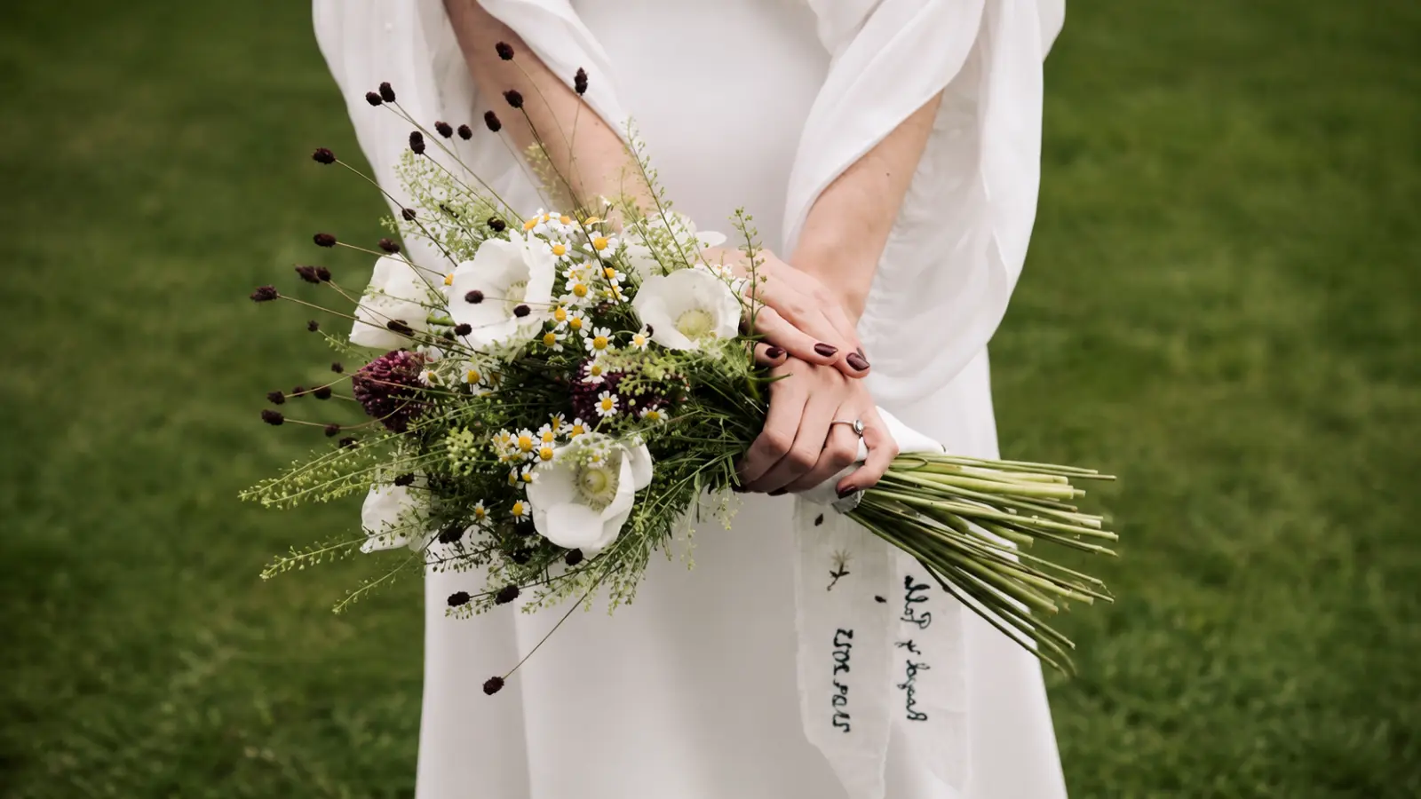 Bride holding a natural winter wedding bouquet with white anemones, chamomile flowers and fresh greenery Winter Wedding Bouquets