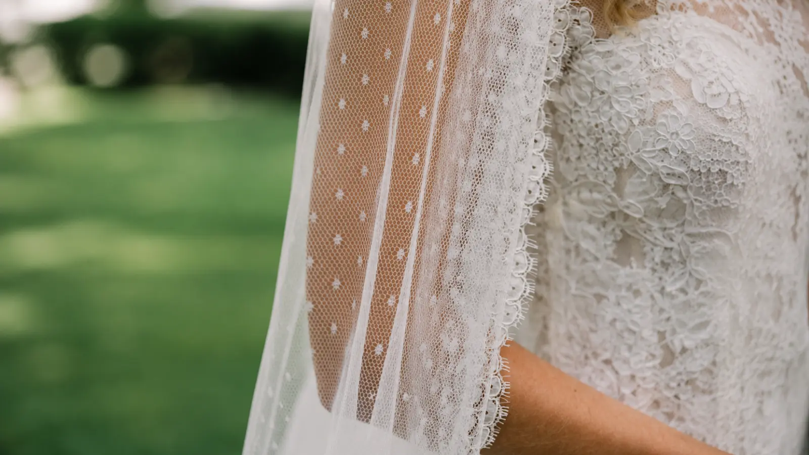 Bride wearing an open back lace wedding dress with a simple sheer veil that complements rather than covers the dress details