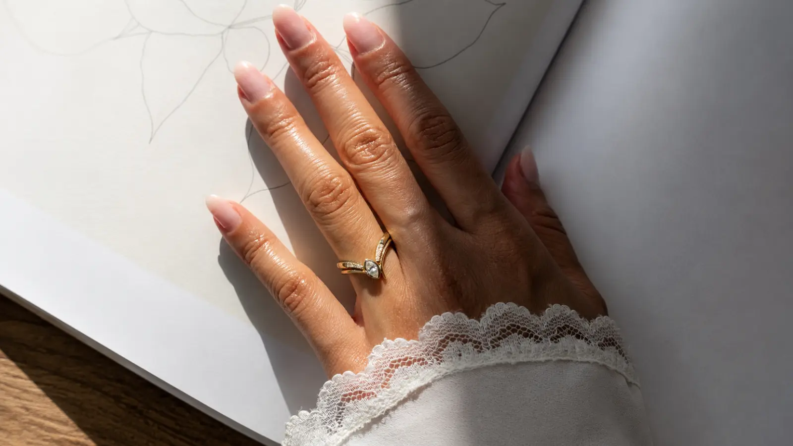 An open wrap wedding band paired with a marquise engagement ring resting on a woman's hand