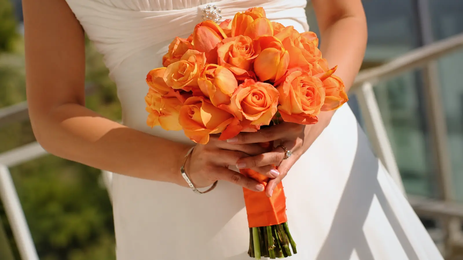 Bride holding an orange wedding bouquets with roses and tulips