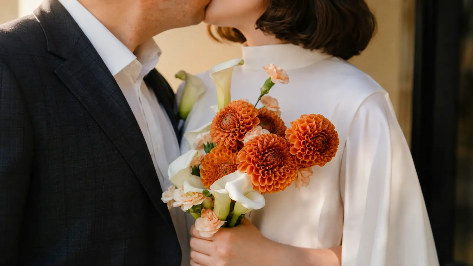 Bride holding an orange rustic wedding bouquet with dahlias and calla lilies