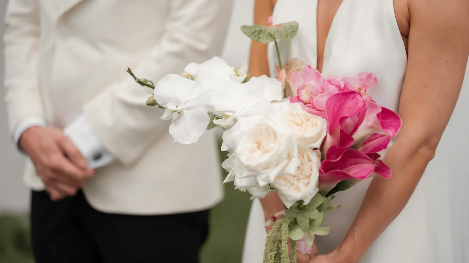 Bride holding a modern wedding bouquet with white orchids and pink calla lilies