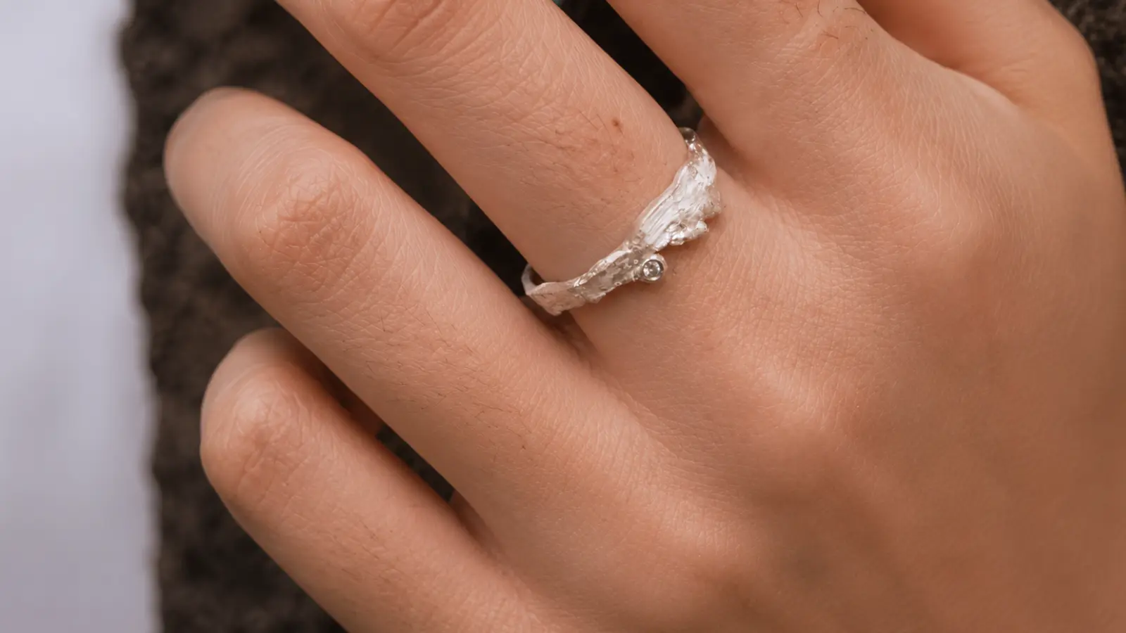 A close-up of an organic floral wedding ring with handcrafted botanical textures and sculptural silver details