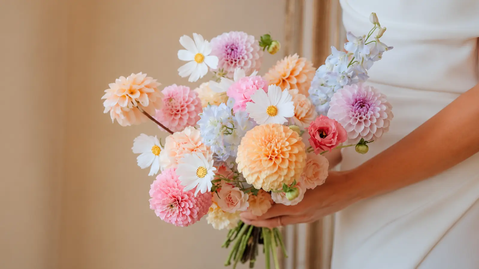 Bride holding a pastel wedding bouquet with dahlias, cosmos and blue delphiniums