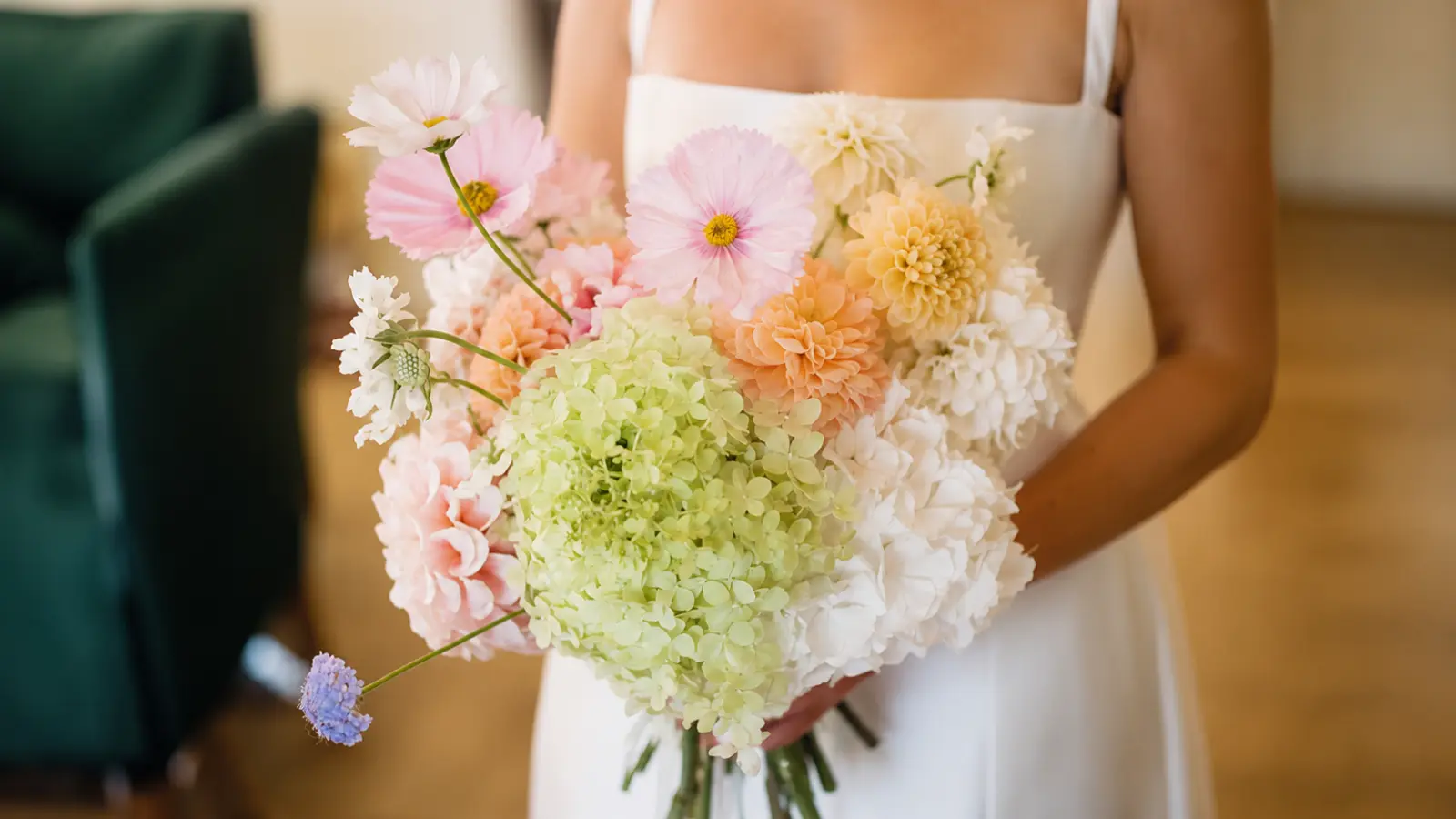 Bride holding a pastel spring wedding bouquet with hydrangea, cosmos and delicate seasonal flowers