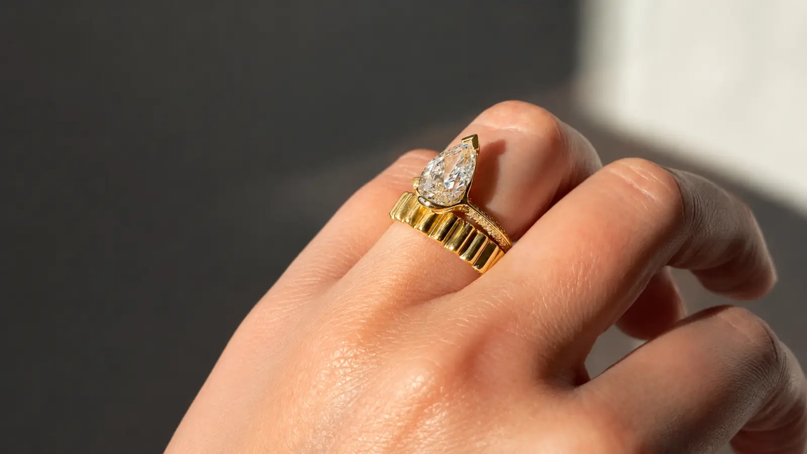A pear cut engagement ring stacked with a ribbed yellow gold band, creating a distinctive and stylish bridal ring combination