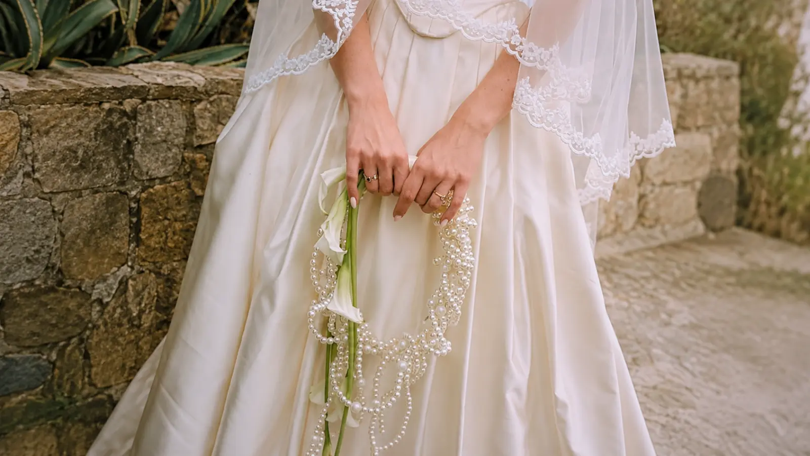 Bride holding a unique wedding bouquets with a pearl handle and white calla lilies