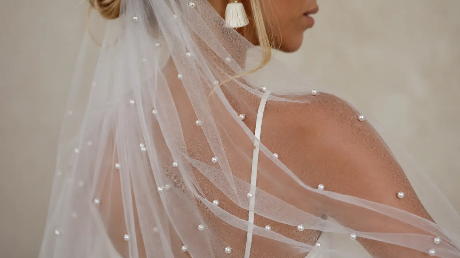 Close-up of a pearl wedding veil with scattered pearls flowing over the bride's shoulder and satin wedding dress Pearl Wedding Veil