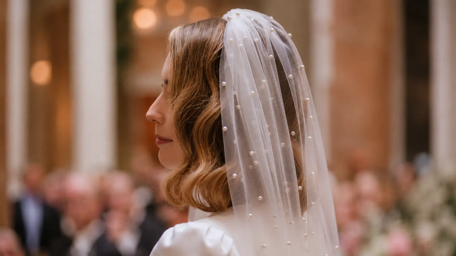 Bride with soft waves wearing a pearl embellished wedding veil during the wedding ceremony
