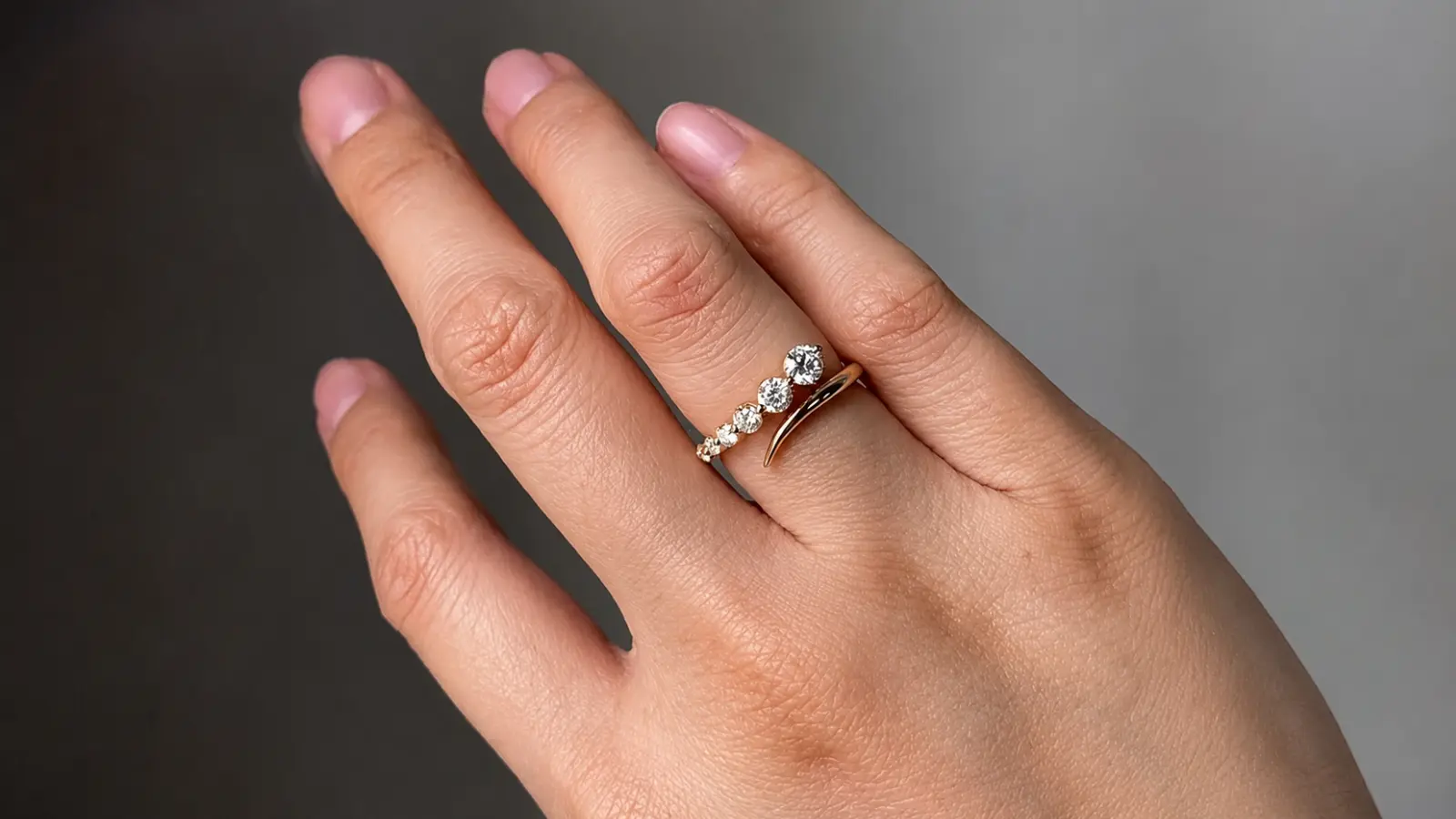 A hand wearing a retro-inspired vintage wedding ring with clustered diamonds and sculptural yellow gold detailing