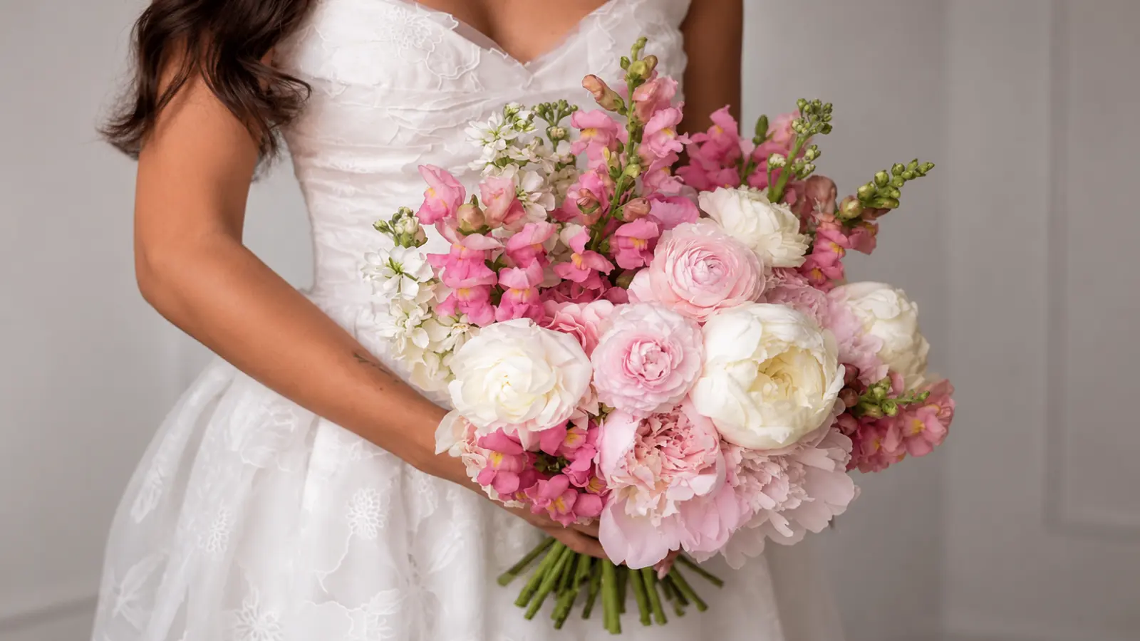 Romantic pink and white wedding bouquet with peonies, garden roses, ranunculus and snapdragons