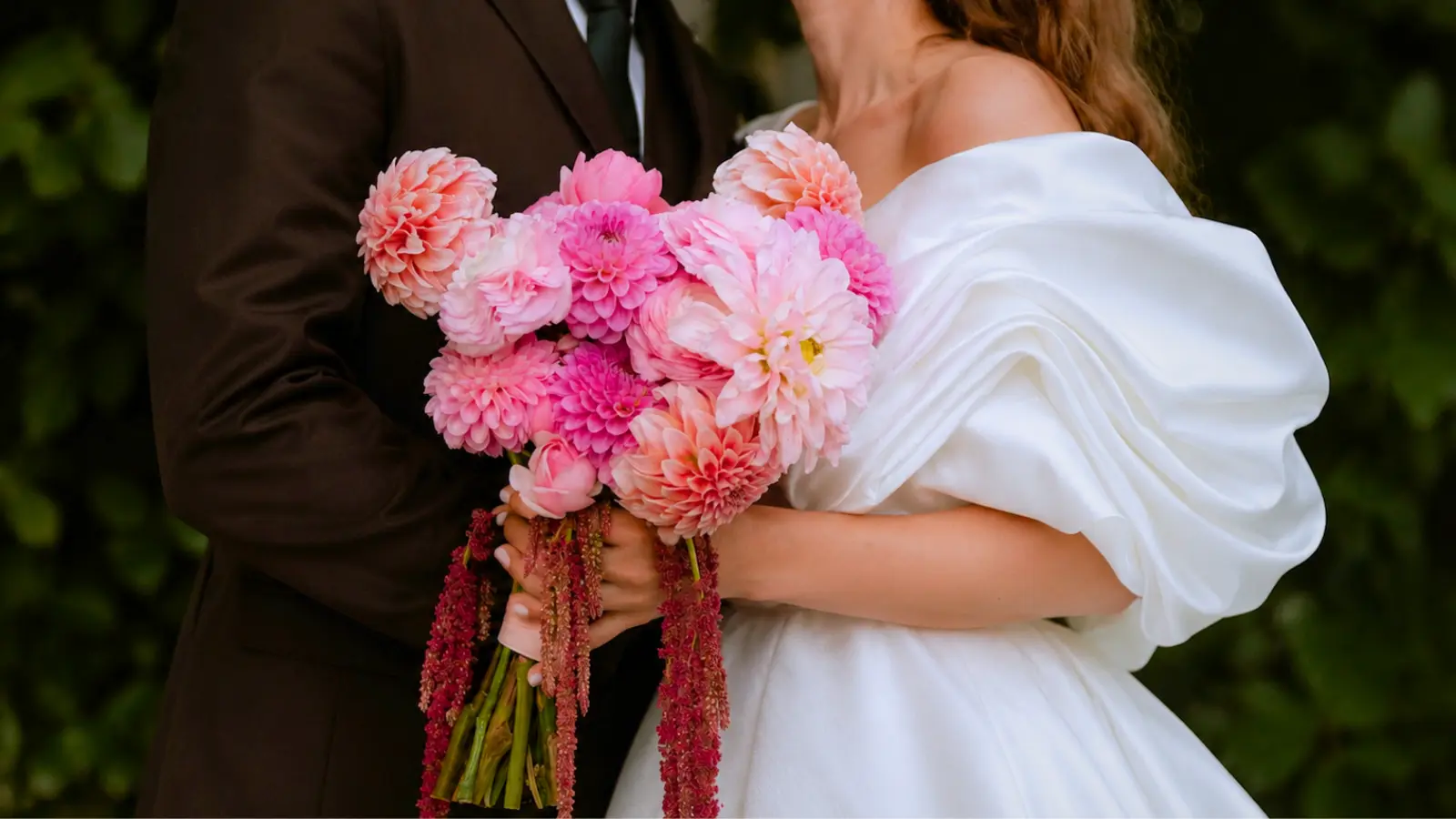 Bride holding a romantic pink dahlia wedding bouquet with blush blooms and cascading burgundy amaranthus