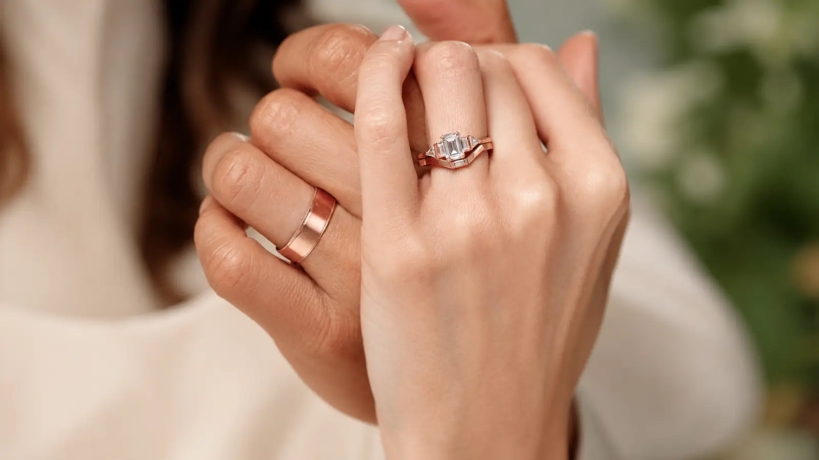 A bride wears a rose gold engagement ring alongside a matching rose gold wedding band, showcasing a coordinated bridal set with elegant styling and warm romantic tones