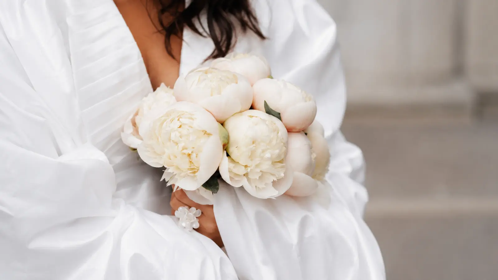 Bride holding a classic round bridal bouquet made with white peonies