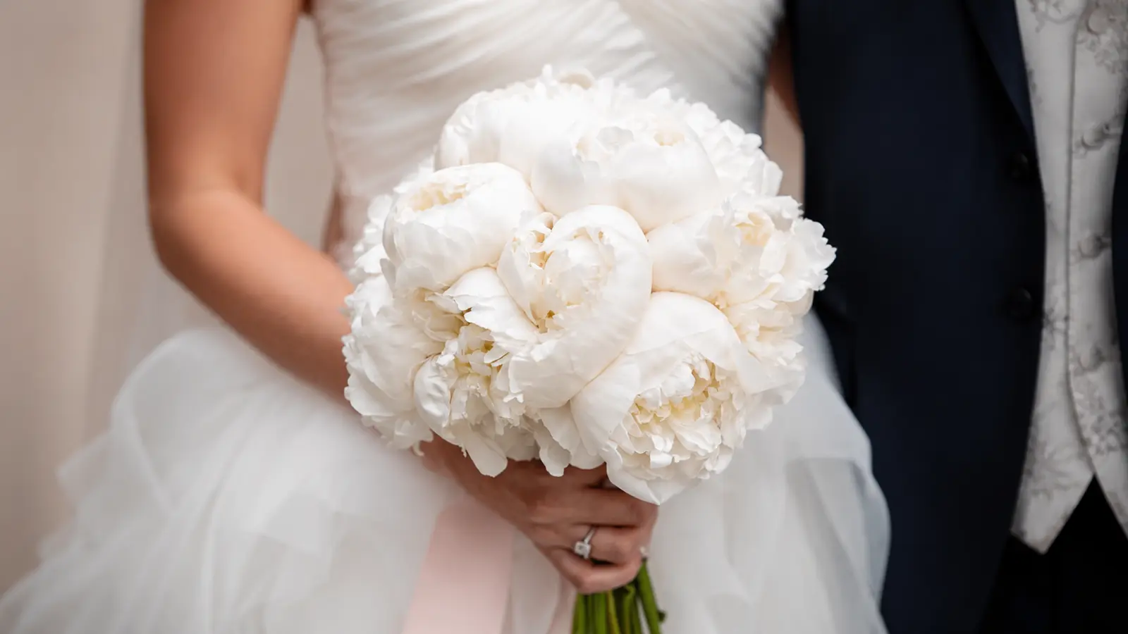 Bride holding a round white peony wedding bouquet with a classic bridal style