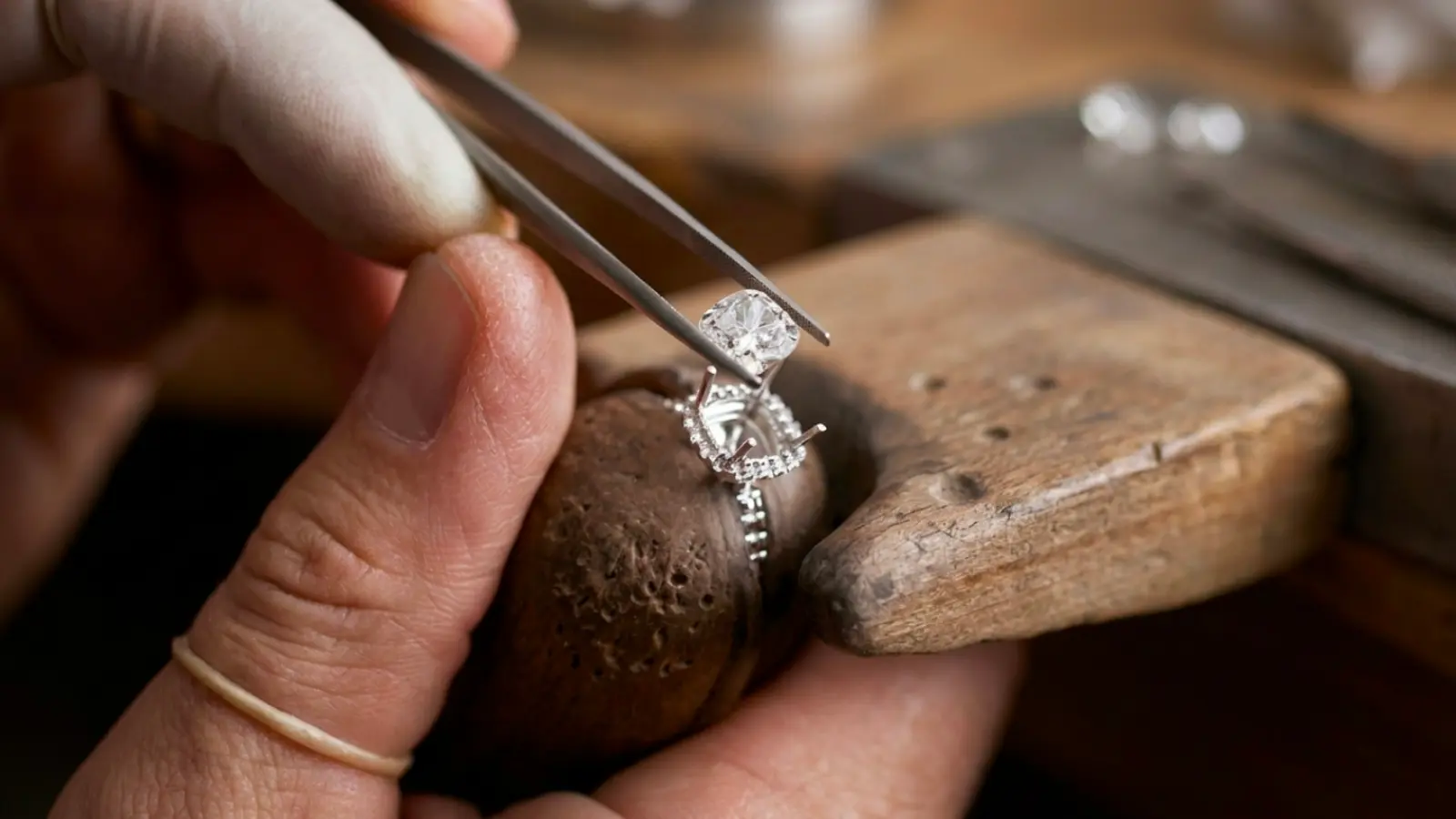 A jeweler using precision tweezers to set a new diamond into an engagement ring during a wedding ring upgrade, enhancing the ring with improved brilliance, craftsmanship, durability, and timeless beauty
