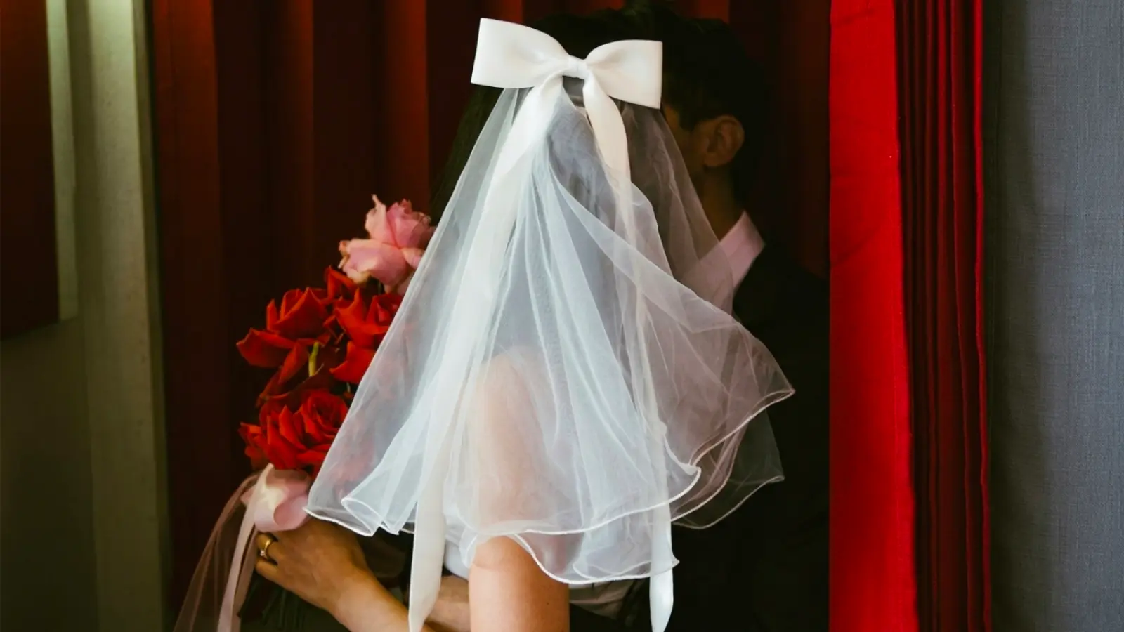 Bride wearing a short wedding veil with a large statement bow, highlighting a modern bridal style that combines soft tulle with contemporary elegance